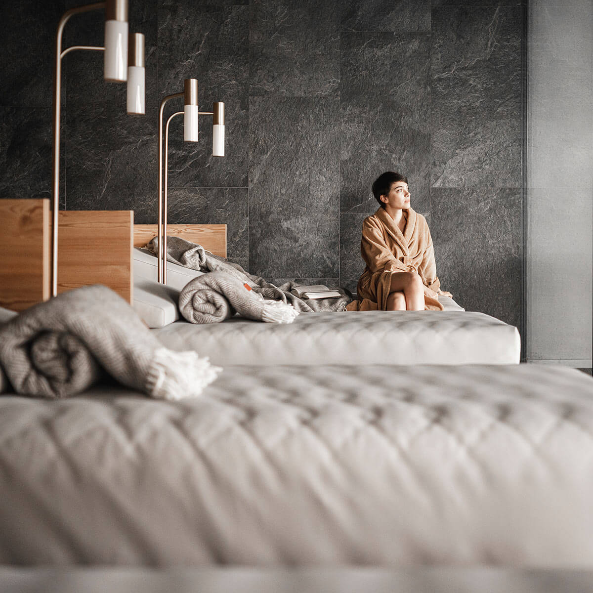 Frau im Bademantel sitzt auf einer Liege